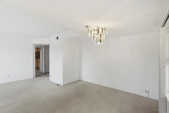 a view of an empty room with chandelier and a window