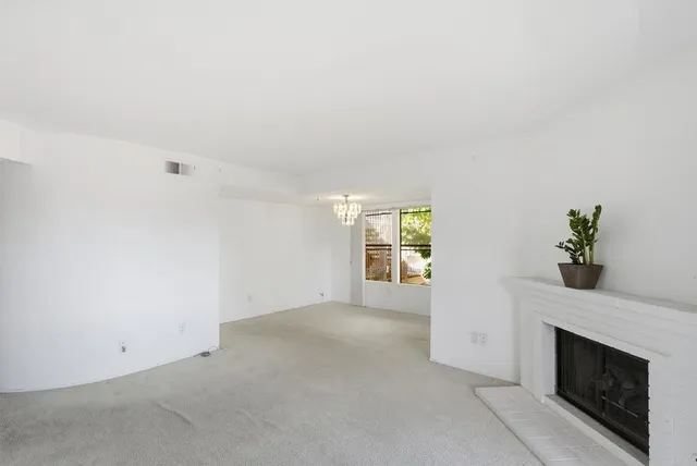 an empty room with windows and fireplace