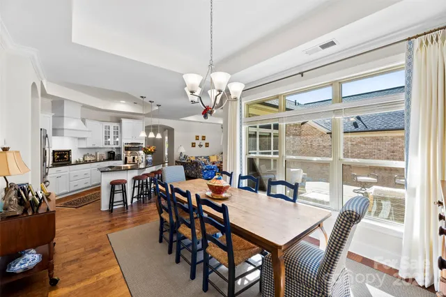 a dining room with wooden floor a chandelier a wooden table and chairs