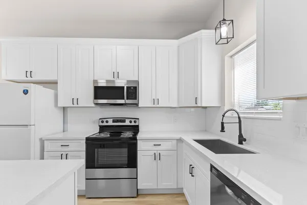 a kitchen with granite countertop white cabinets and stainless steel appliances