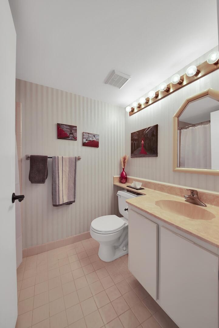4708 Lucerne Lakes Boulevard East, Unit 104 Lake Worth, FL 33467 - Photo 20 of 28 a bathroom with a sink toilet and mirror