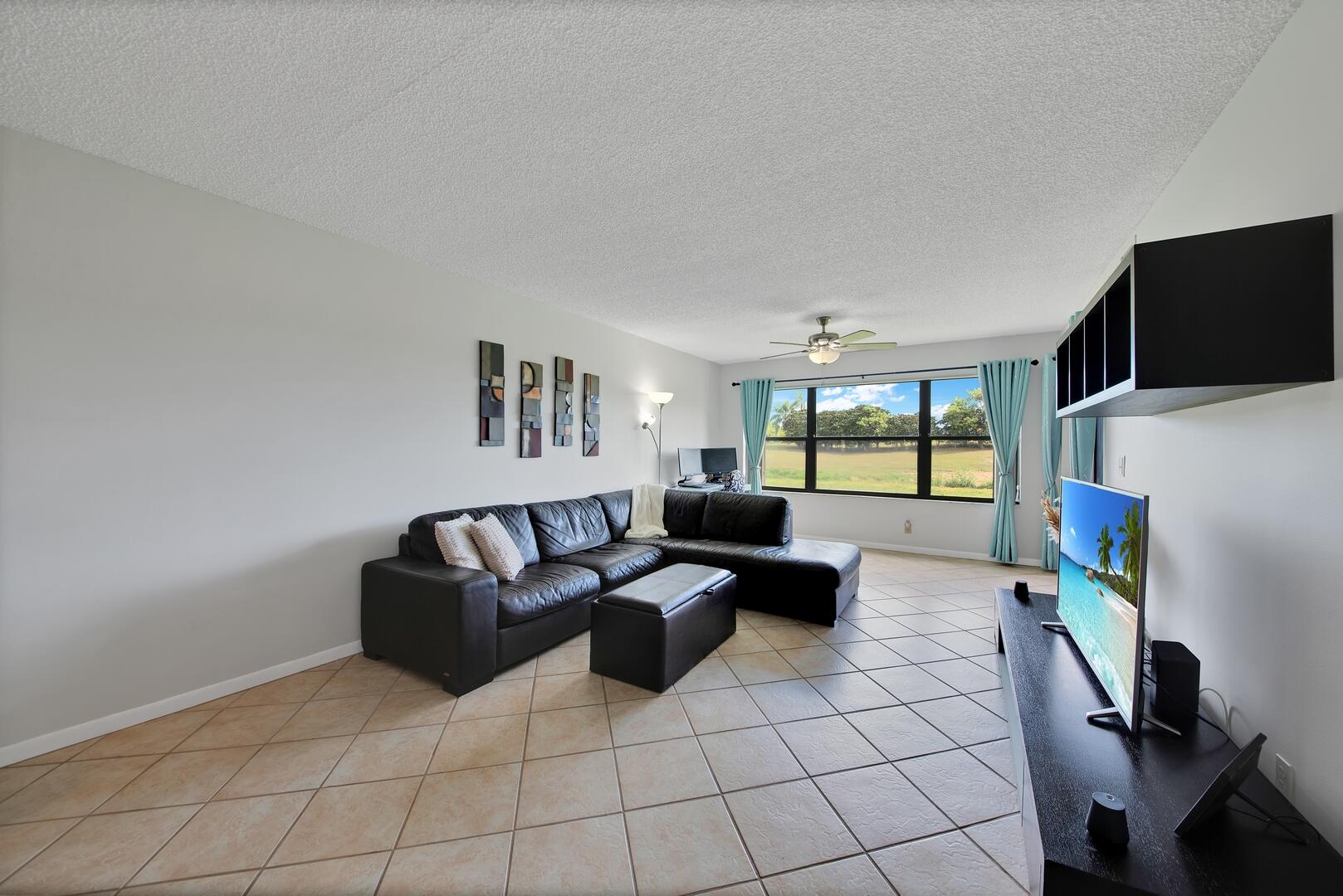 4708 Lucerne Lakes Boulevard East, Unit 104 Lake Worth, FL 33467 - Photo 7 of 28 a living room with furniture and a flat screen tv