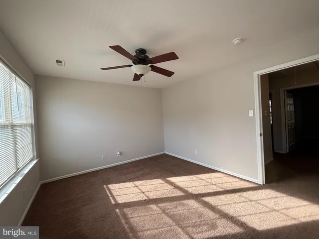 an empty room with a window and a ceiling fan