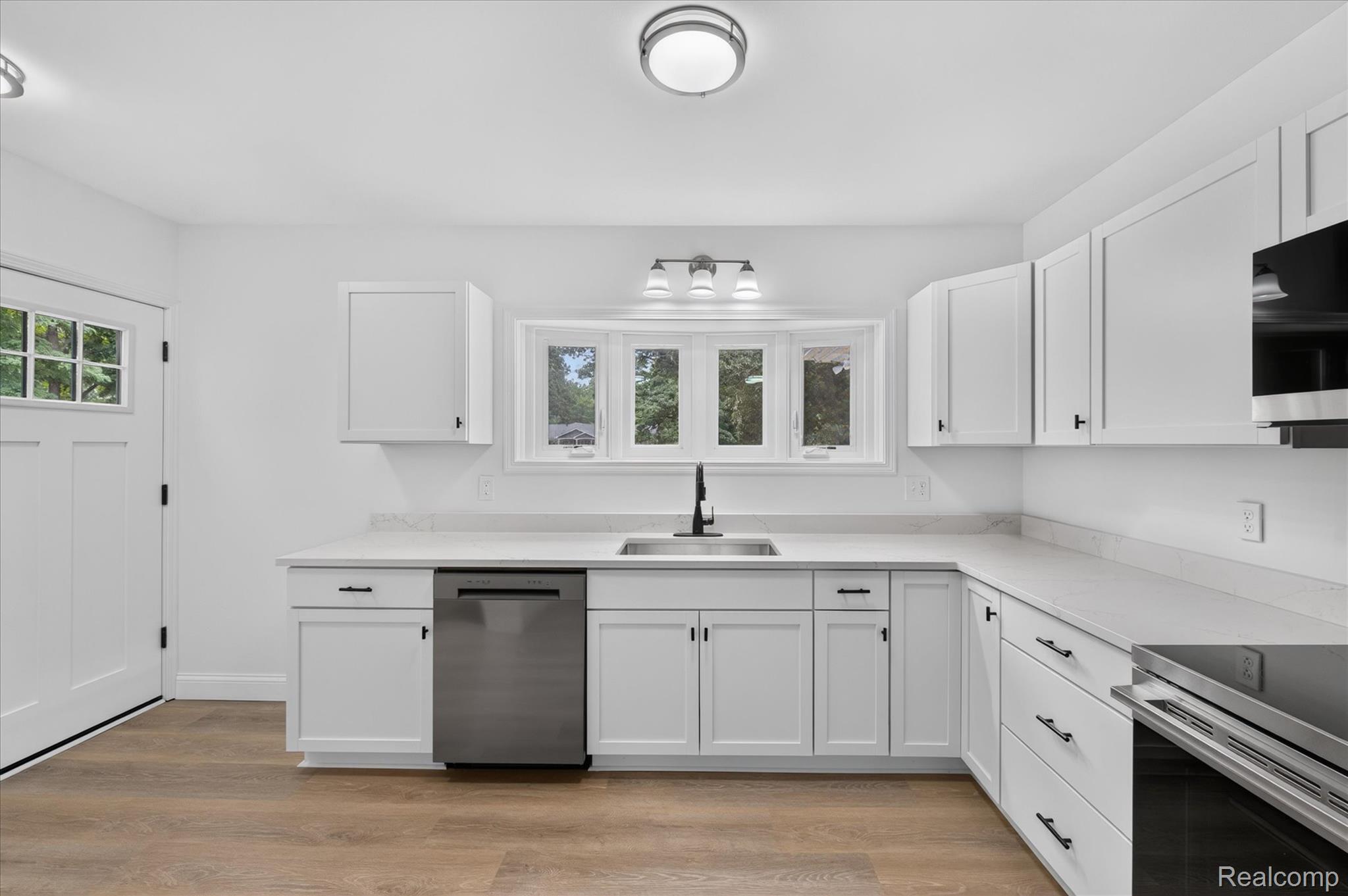 11403 White Lake Road Fenton, MI 48430 - Photo 10 of 36 White shaker-style cabinetry with matte black hardware, stainless steel appliances, and light-toned countertops
