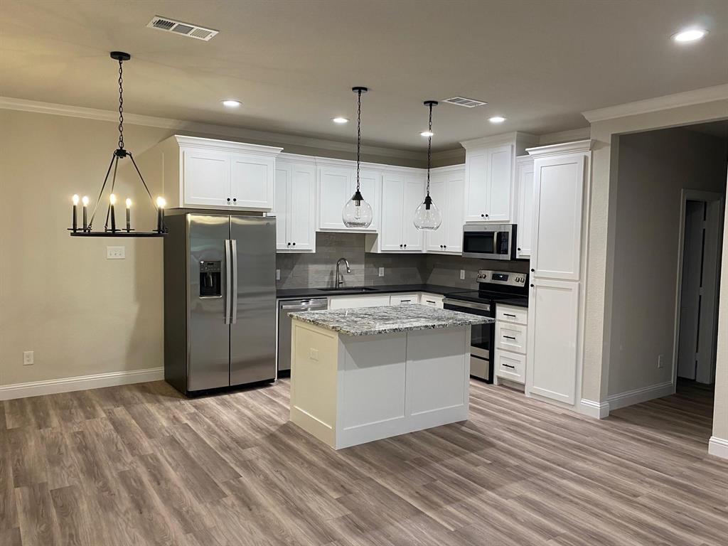403 South 6th Street, Unit B Midlothian, TX 76065 - Photo 4 of 9 a kitchen with stainless steel appliances granite countertop a refrigerator a stove a sink and a wooden floor