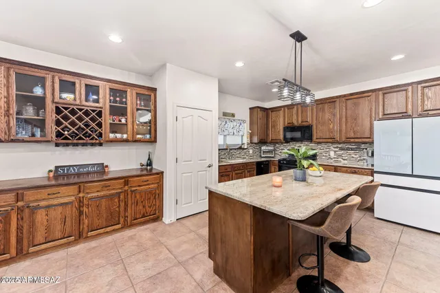 a kitchen with stainless steel appliances a stove a refrigerator a sink a center island and chairs