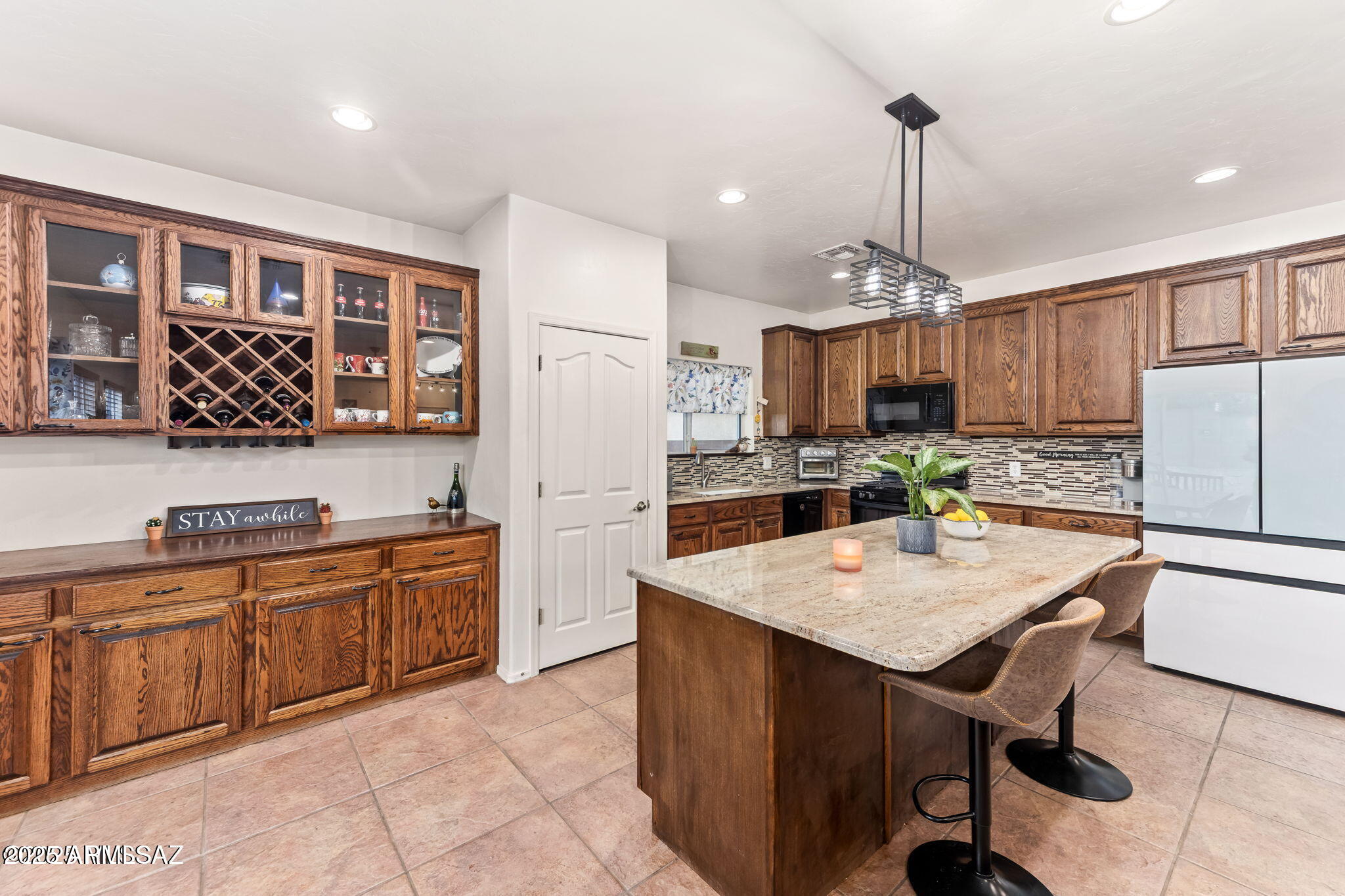 3635 East Secretariat Road Tucson, AZ 85739 - Photo 6 of 27 a kitchen with stainless steel appliances a stove a refrigerator a sink a center island and chairs