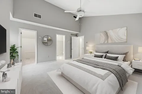 a spacious bedroom with a bed and a potted plant on the dresser