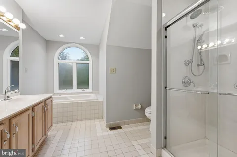 a view of a hallway with wooden floor and a bathroom
