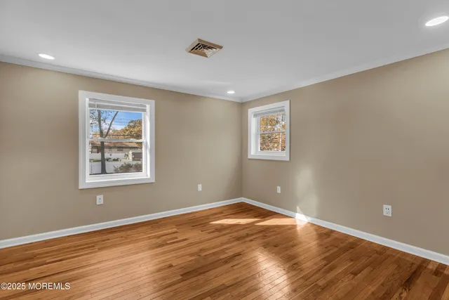 a view of a big room with wooden floor and windows