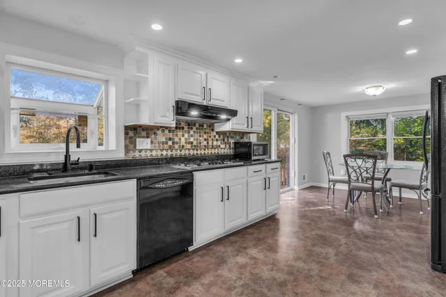 a kitchen with stainless steel appliances granite countertop a stove a sink a oven a dining table and chairs