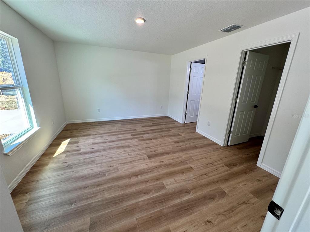 8601 North Stern Drive Citrus Springs, FL 34434 - Photo 7 of 18 an empty room with wooden floor and windows
