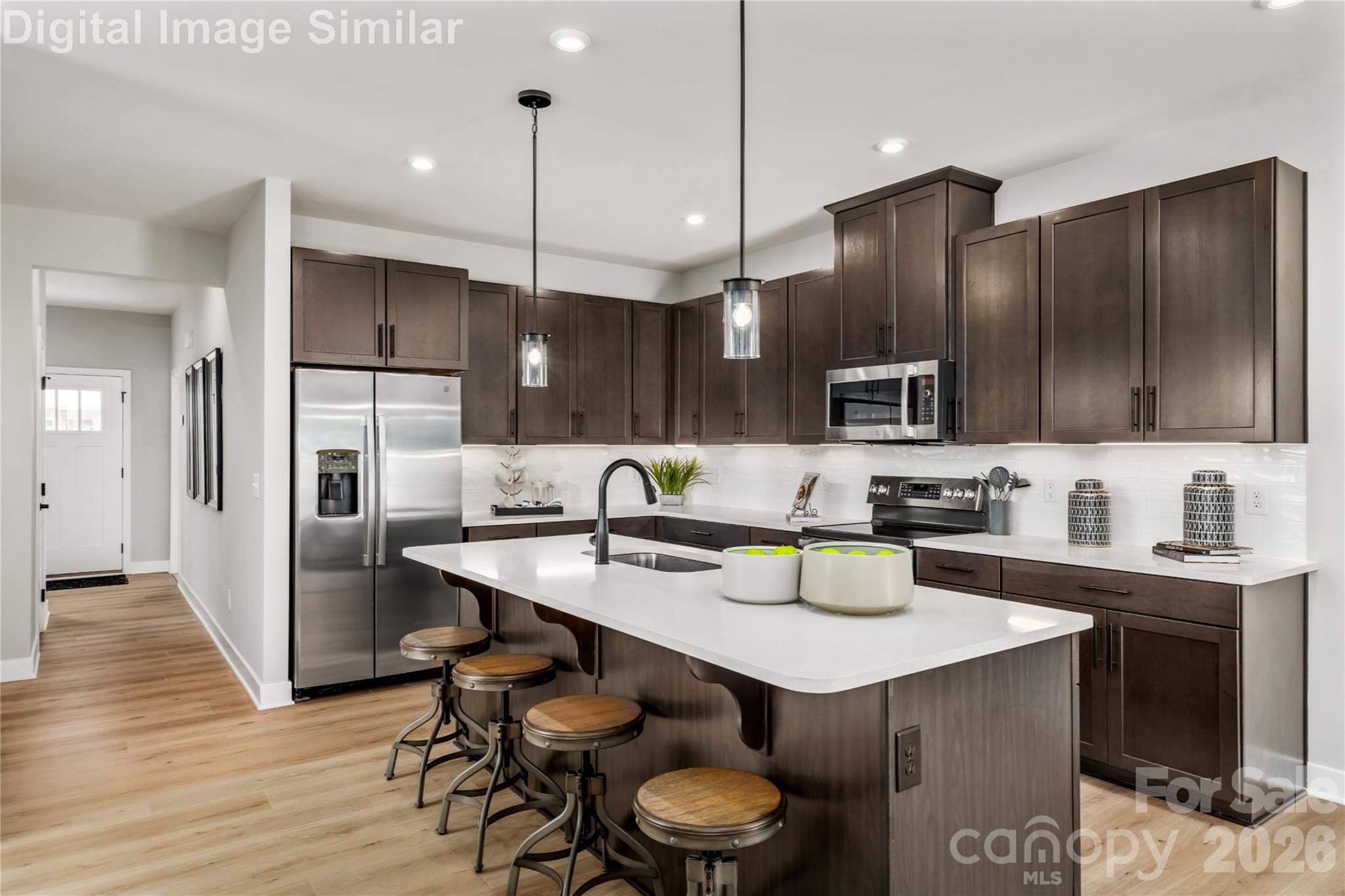 9569 Teamwork Street Northwest Concord, NC 28027 - Photo 3 of 23 a kitchen with stainless steel appliances kitchen island granite countertop a sink a stove a refrigerator and chairs with wooden floor