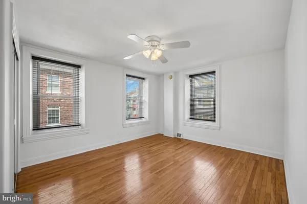a view of an empty room with a window and wooden floor