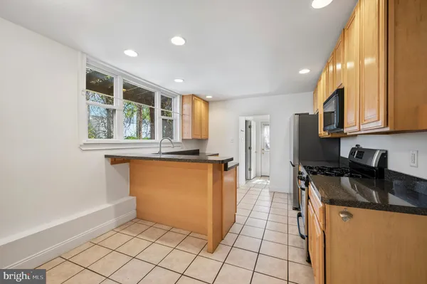a kitchen with granite countertop a refrigerator and a stove top oven
