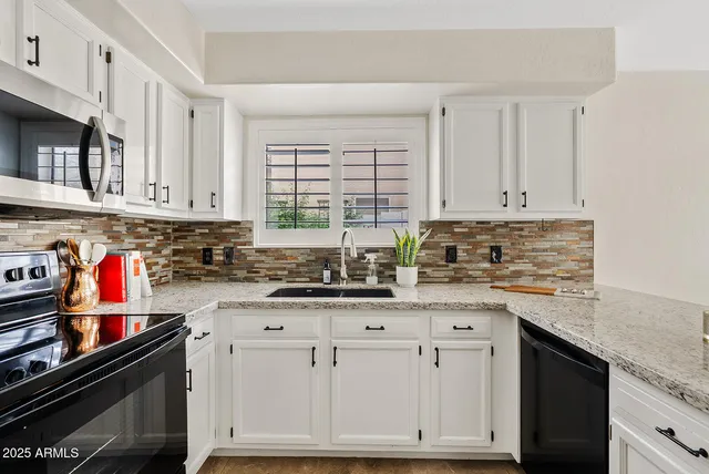 a kitchen with granite countertop a sink cabinets and stainless steel appliances