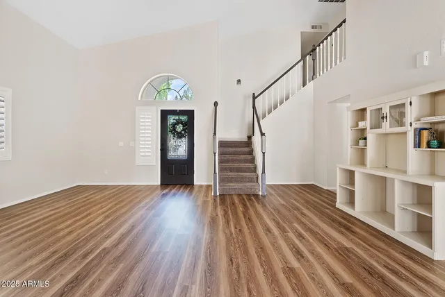 a view of empty room with stairs and wooden floor