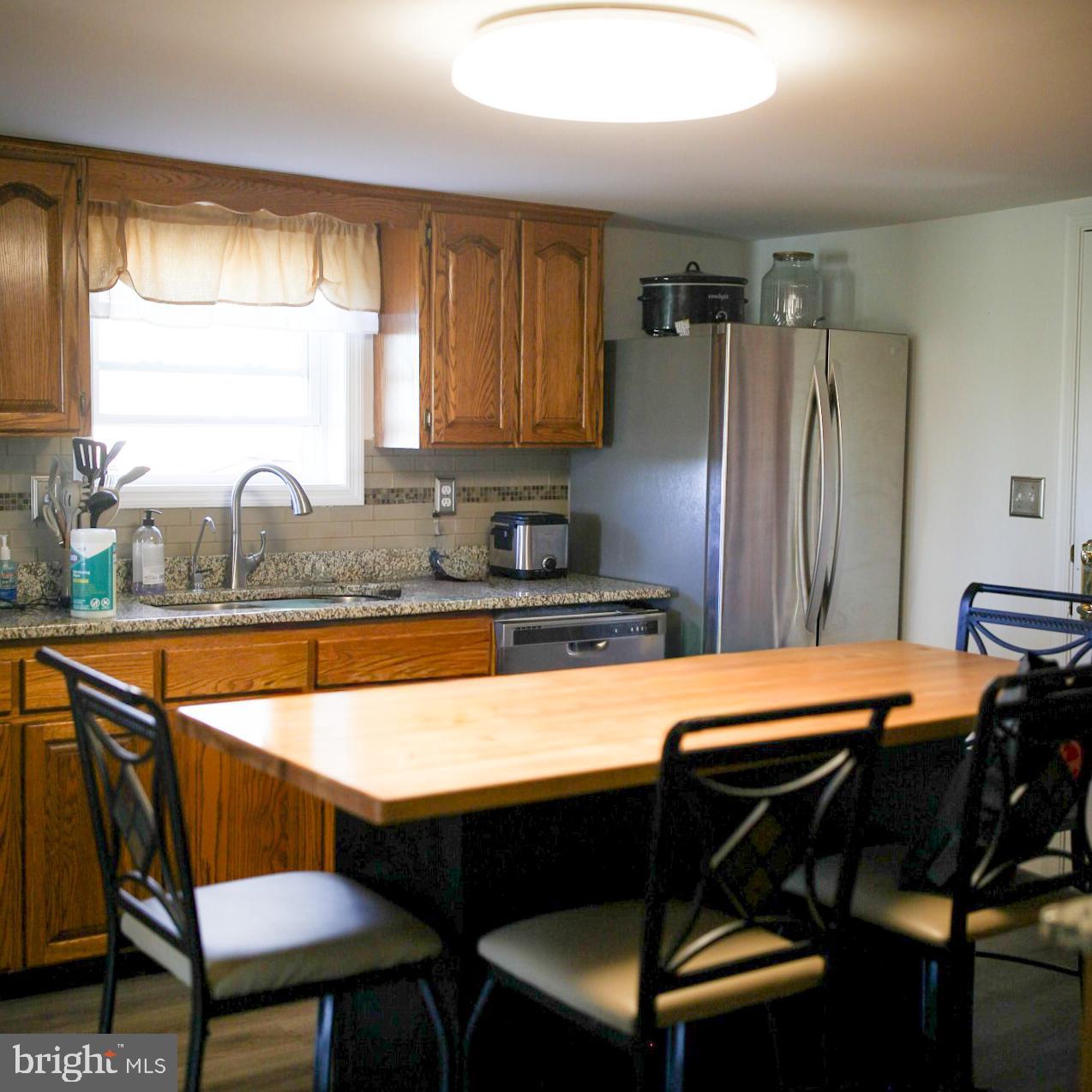 7308 Federalsburg Road Bridgeville, DE 19933 - Photo 15 of 24 a kitchen with stainless steel appliances granite countertop white refrigerator a sink dishwasher and wooden cabinets