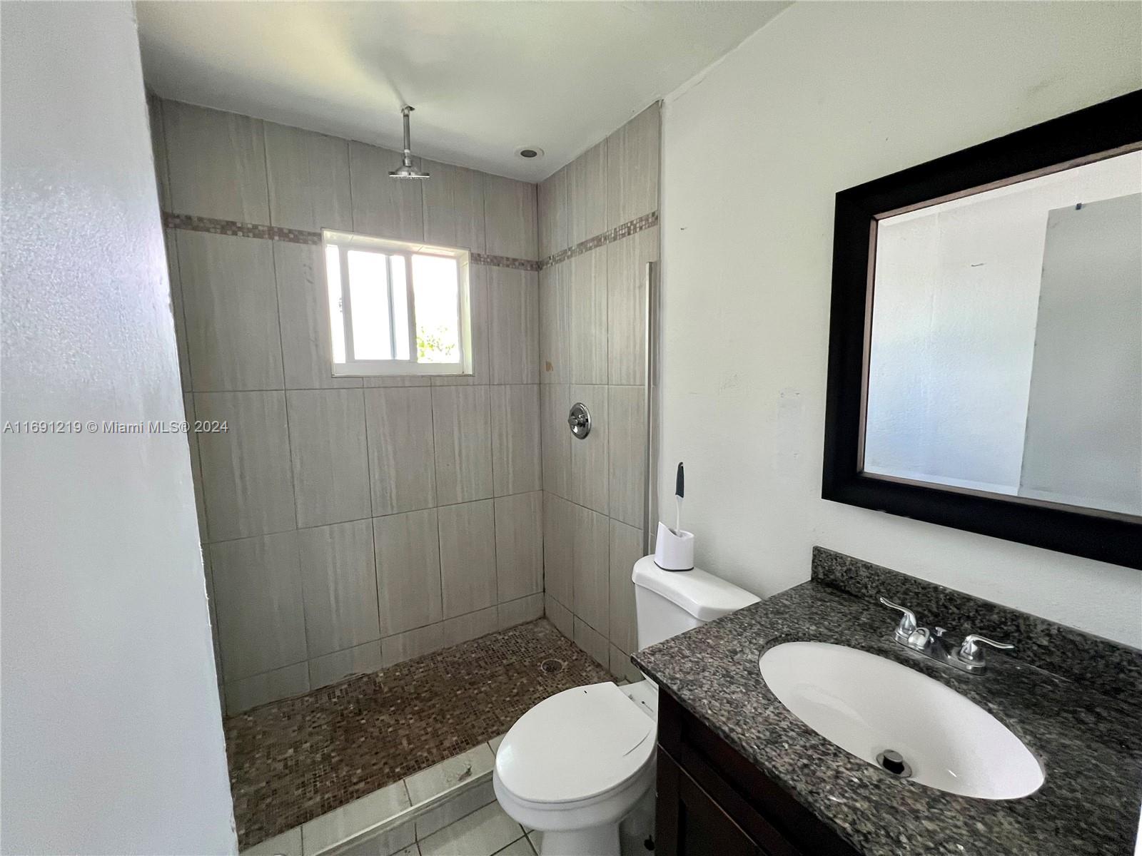 37 Southwest 14th Street, Unit 16 Dania Beach, FL 33004 - Photo 8 of 11 a bathroom with a granite countertop sink toilet a mirror and shower