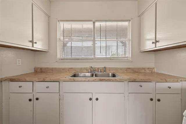 a kitchen with granite countertop white cabinets and a sink