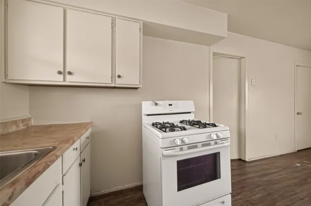 a kitchen with granite countertop white cabinets and white stove