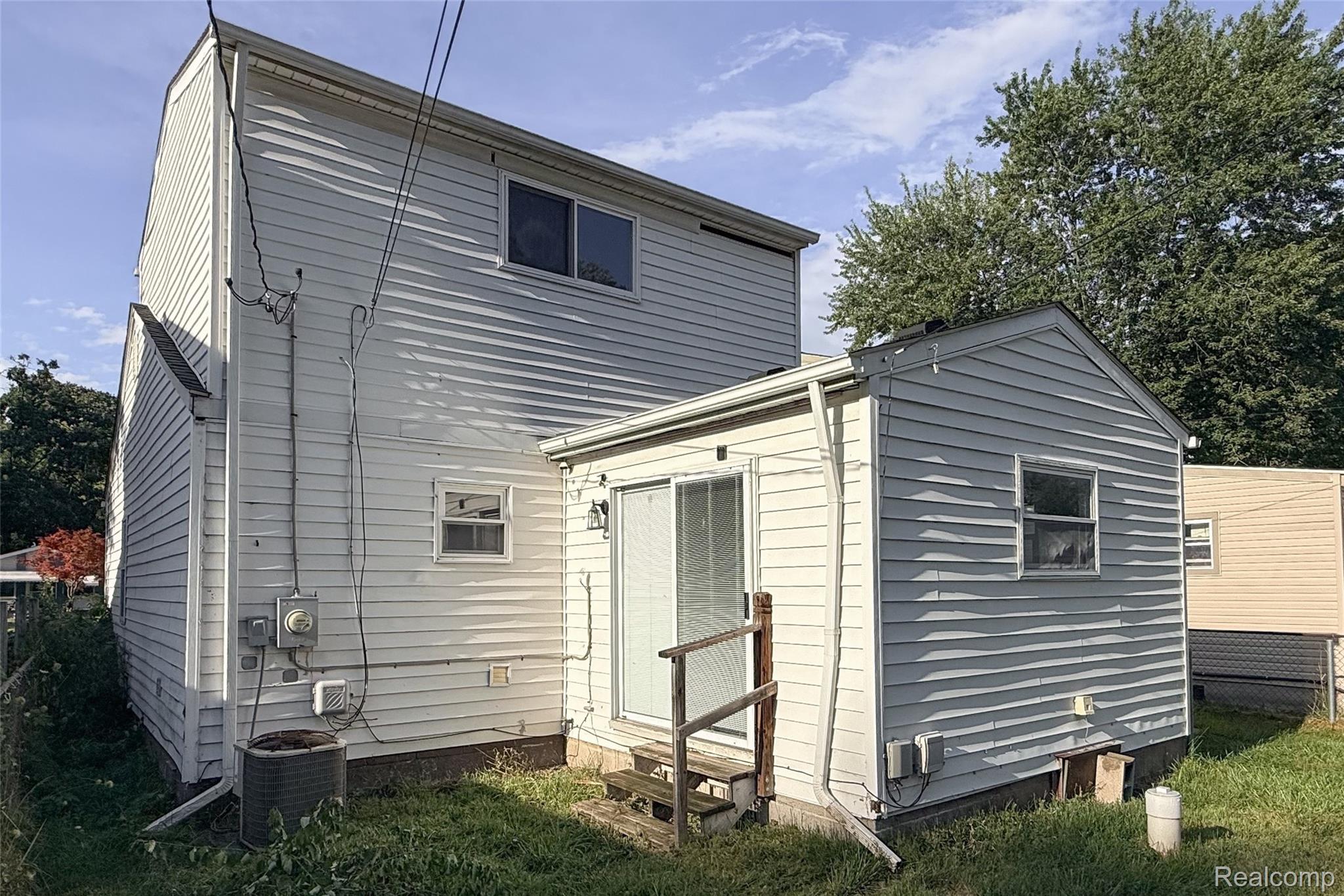 26137 Superior Road Taylor, MI 48180 - Photo 8 of 34 White vinyl siding exterior with a sliding glass door and an attached single-story structure