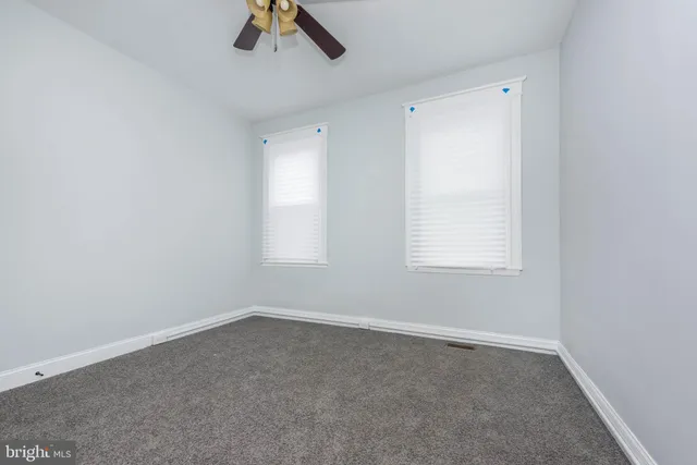 an empty room with a window and a ceiling fan