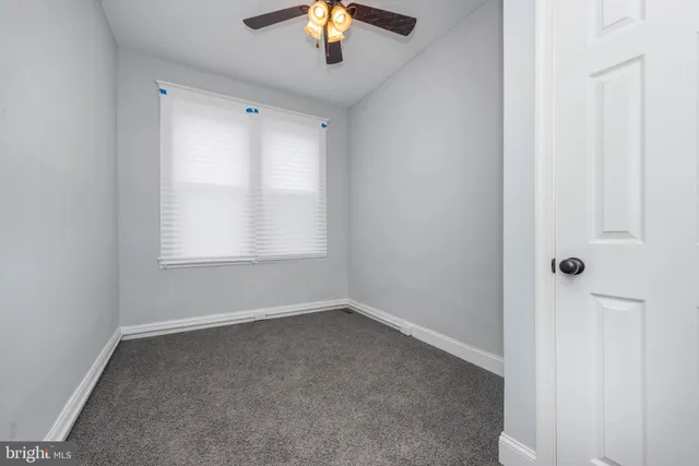 an empty room with a window and a fan