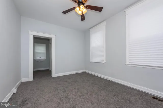 an empty room with windows and chandelier fan