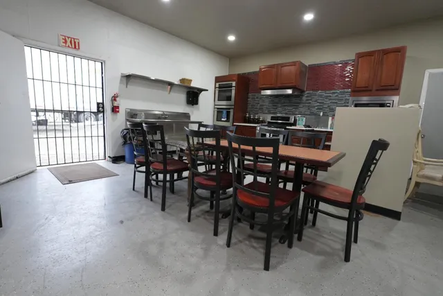 a kitchen with kitchen island a dining table chairs and a refrigerator