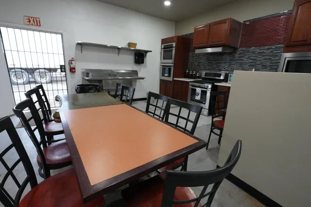 a kitchen with stainless steel appliances a dining table chairs a refrigerator and a stove