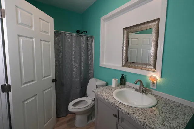 a bathroom with a granite countertop sink toilet and mirror