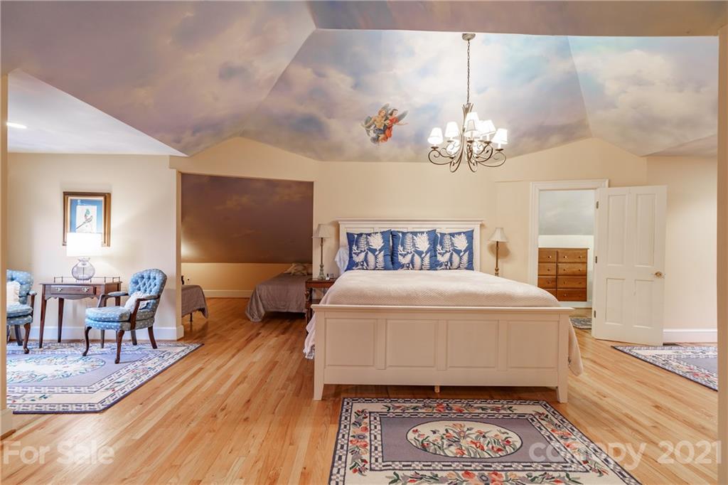454 Cut Away Road Lake Lure, NC 28746 - Photo 32 of 48 a spacious bedroom with a bed and a chandelier