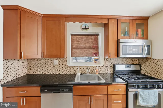 a kitchen with granite countertop a stove top oven cabinetry a sink and a window