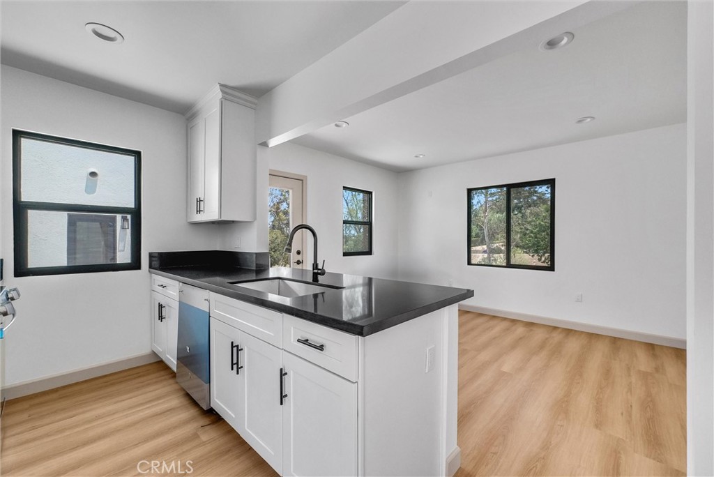 5090 Rockledge Drive Riverside, CA 92506 - Photo 31 of 40 a kitchen with granite countertop a sink and dishwasher with wooden floor