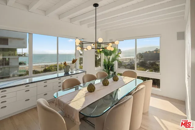 a living room with furniture hard wood floor and a floor to ceiling window