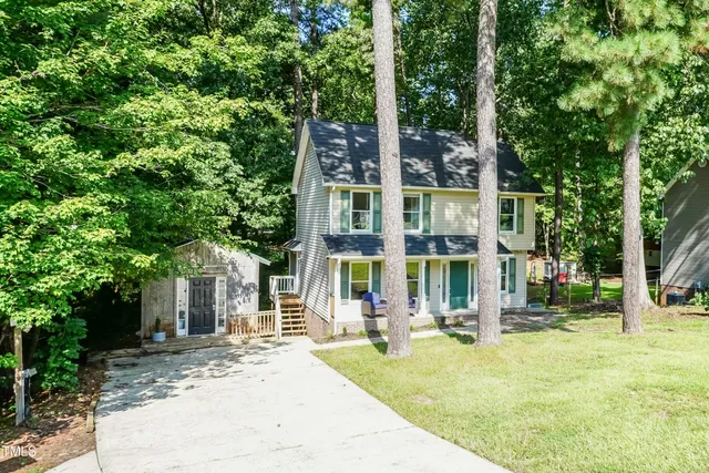 a front view of a building with garden and trees