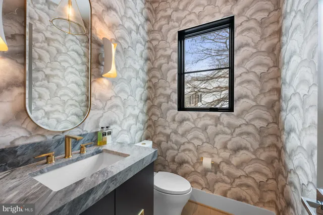 a bathroom with a granite countertop toilet a sink and a mirror