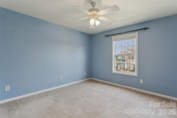 an empty room with windows and ceiling fan