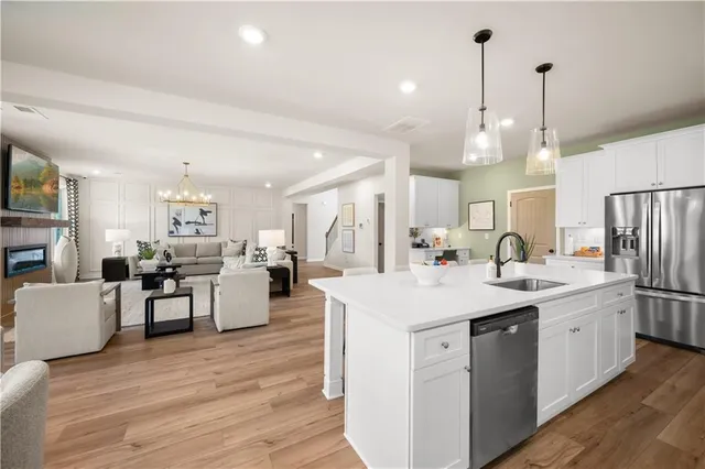 a large white kitchen with lots of counter space dining table and stainless steel appliances