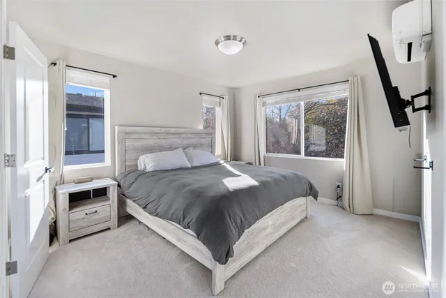 a bedroom with a bed next to a window with a chair