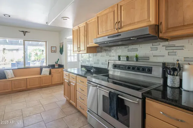 a kitchen with stainless steel appliances granite countertop a stove a sink and a white cabinets