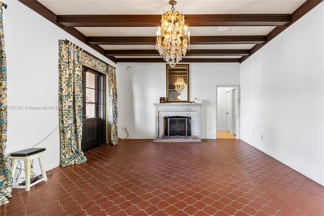 a view of an empty room with a fireplace and a chandelier