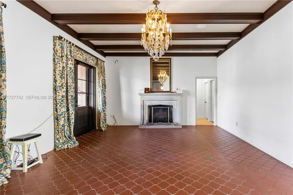 a view of an empty room with a fireplace and a chandelier