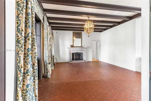 a view of empty room with floor to ceiling window and fireplace
