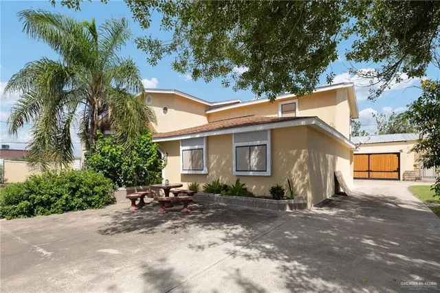 a backyard of a house with table and chairs under palm trees