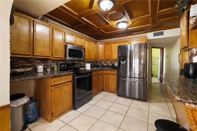 a kitchen with granite countertop a refrigerator and a stove top oven