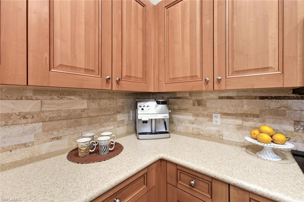 10800 Fieldfair Drive Naples, FL 34119 - Photo 10 of 47 Kitchen with light stone counters, decorative backsplash, and brown cabinets