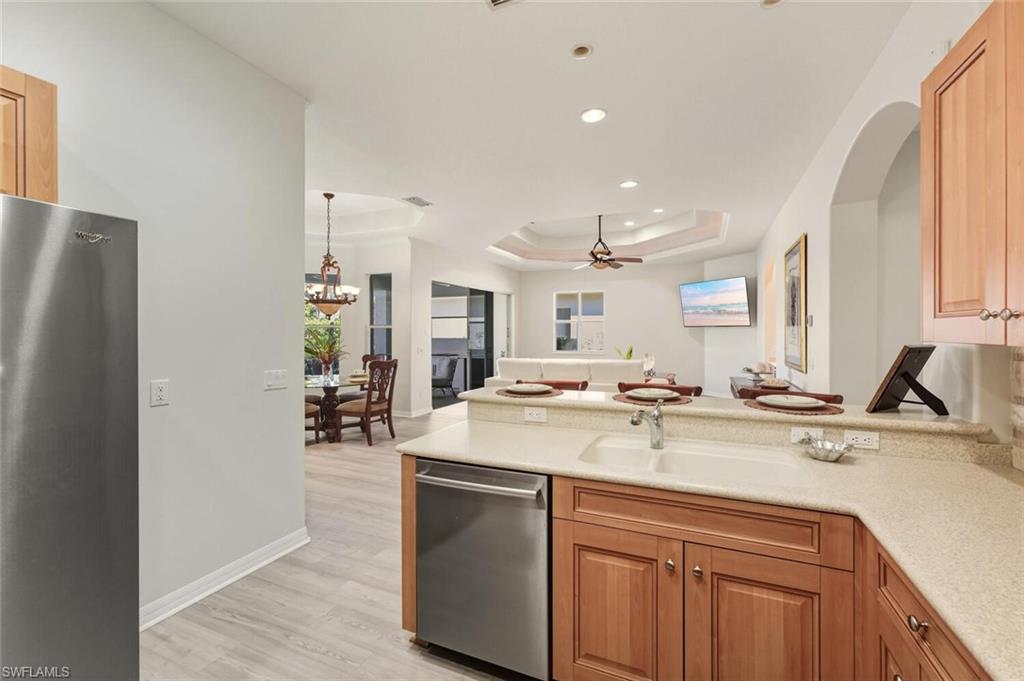 10800 Fieldfair Drive Naples, FL 34119 - Photo 11 of 47 Kitchen featuring a peninsula, stainless steel appliances, a raised ceiling, ceiling fan, and light wood-style flooring