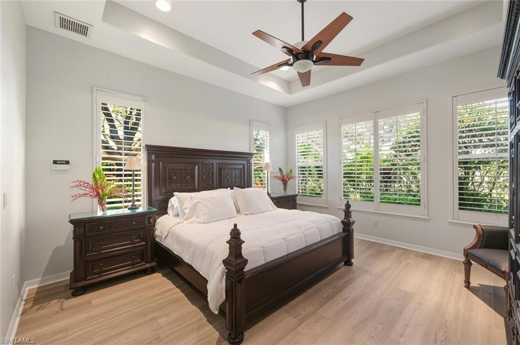10800 Fieldfair Drive Naples, FL 34119 - Photo 17 of 47 Bedroom with a tray ceiling, light wood finished floors, a ceiling fan, multiple windows, and recessed lighting